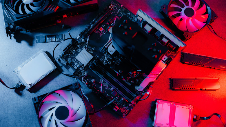A collection of computer hardware parts including a GPU, power supply, and RAM laid out on a table.