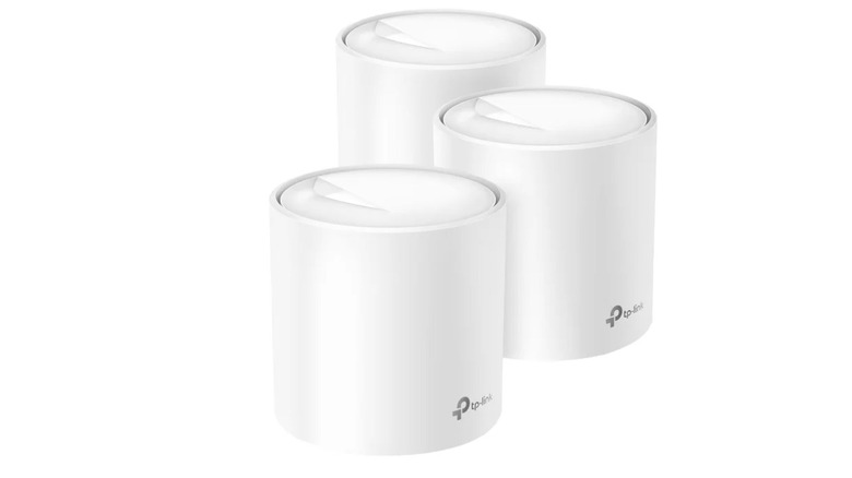 Three identical white TP-Link mesh Wi-Fi routers standing in a row.