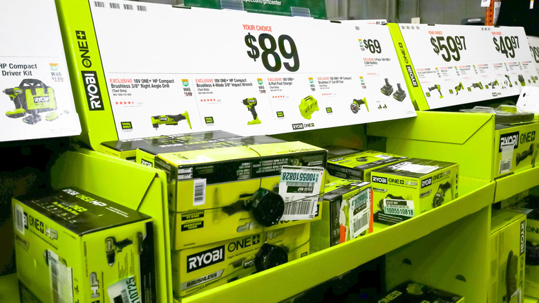 Multiple Ryobi tool bundles and boxed sets stacked on a retail shelf.