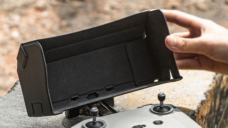 A drone remote controller equipped with a foldable sun hood to reduce screen glare.