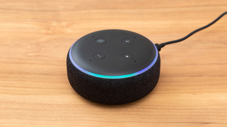 A black Amazon Echo device on a wooden countertop.