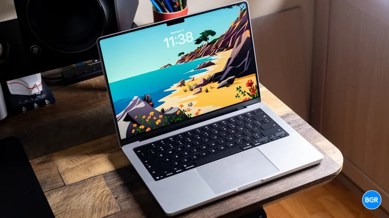 A professional M5 Max MacBook Pro on a wooden desk environment.