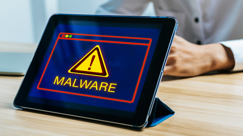A close-up of a tablet screen displaying a red security alert warning for malware.