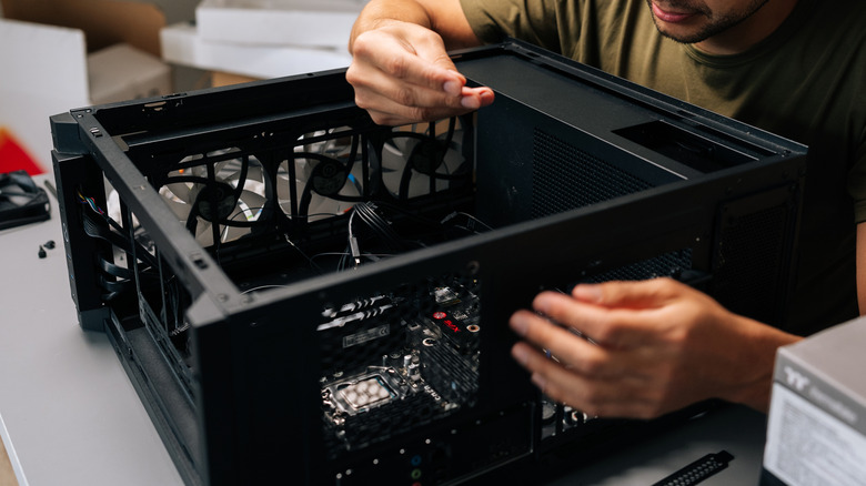 A person working on the internal components of a desktop PC case.