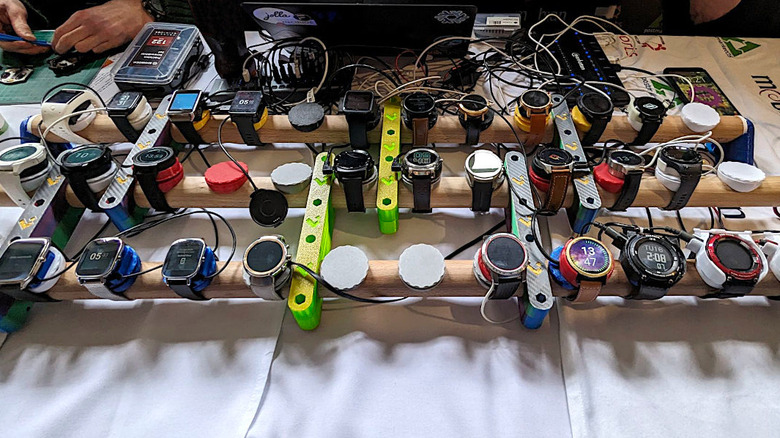 Several smartwatches running the AsteroidOS interface displayed on a table.