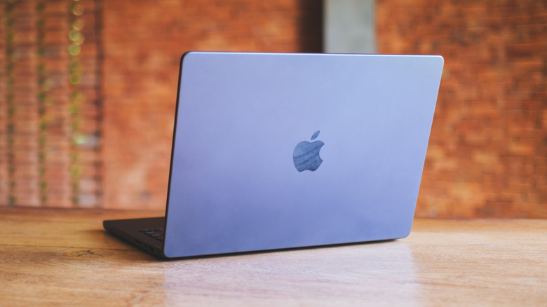 An Apple MacBook Pro laptop open on a clean wooden table in a professional setting.
