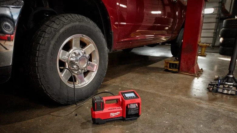 Close-up of the M18 Cordless Tire Inflator next to a car tire with the hose attached.