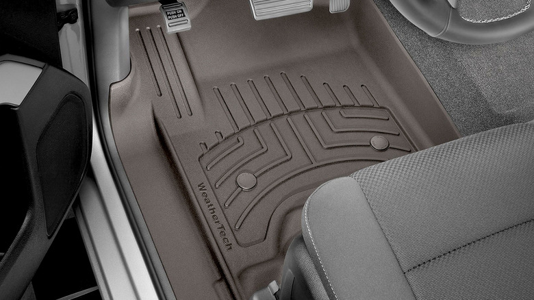 Close-up of a premium floor mat installed at the driver's feet with visible pedals.