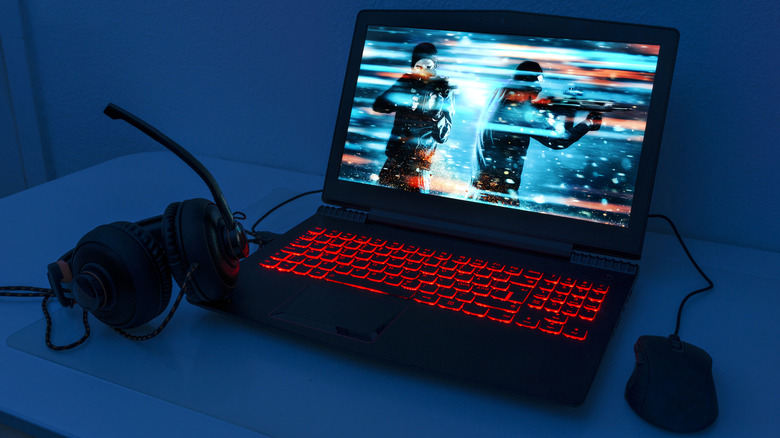 A gaming laptop on a dedicated desk with a clean peripheral setup and ergonomic lighting.
