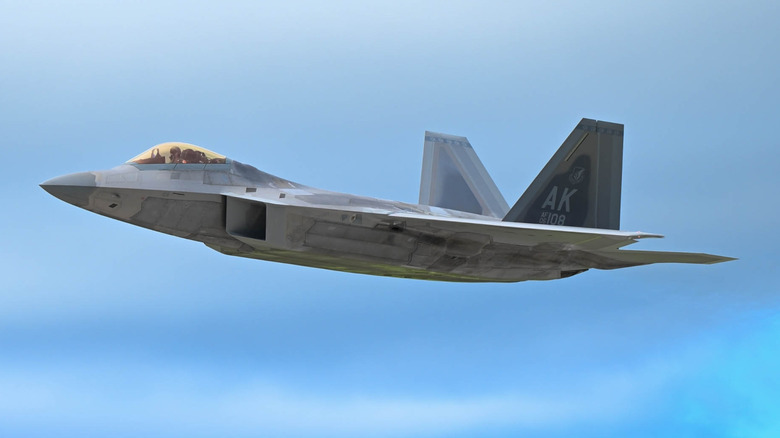 An F-22 Raptor in a banking turn, showcasing its curved, radar-absorbent airframe.