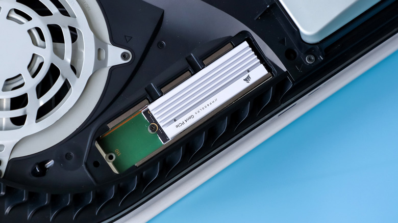 A white Corsair M.2 SSD with a heatsink installed in the PlayStation 5 internal expansion slot.