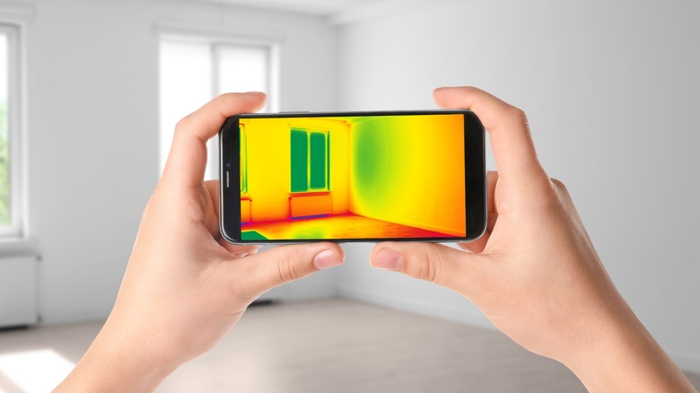 Close-up of a smartphone screen displaying a color-coded thermal heat map of an indoor space.