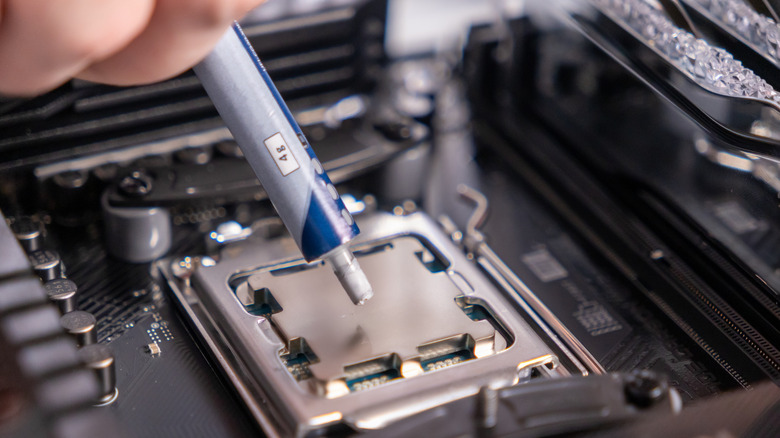 A close-up of thermal paste being applied to the center of a desktop processor.