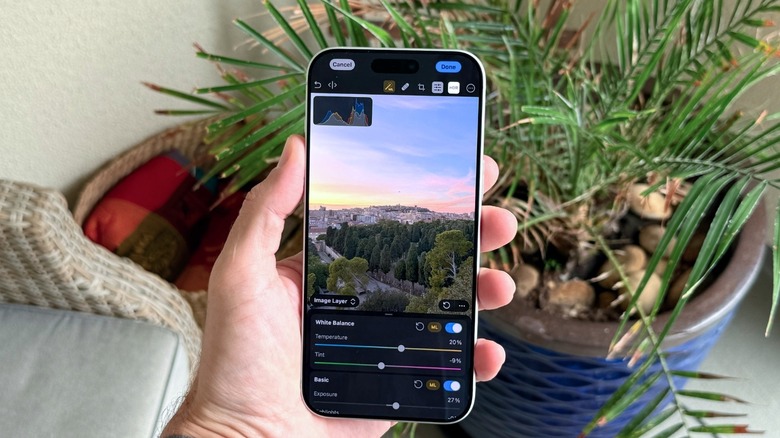 A hand holding an iPhone while using the Photomator app to edit a high-quality photograph.