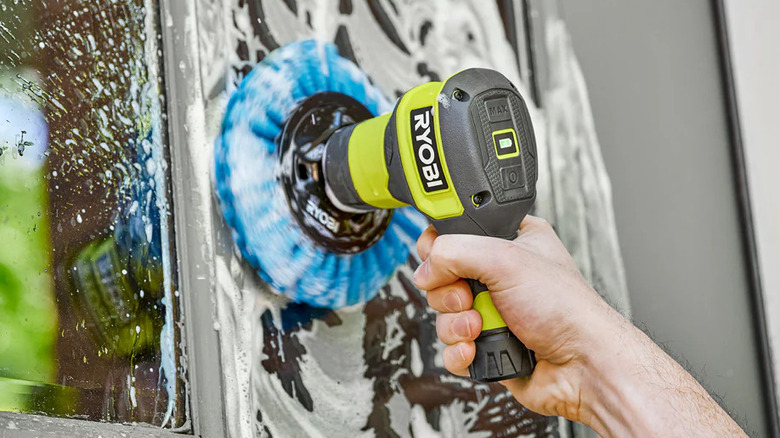 A person using the Ryobi USB Lithium power scrubber to clean a window frame.