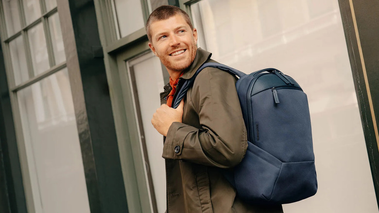 A person wearing a navy blue backpack while walking outdoors.