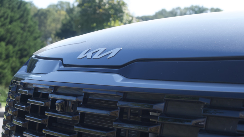 Close-up of the Kia badge and textured grille on the front of the 2026 Sportage Hybrid.