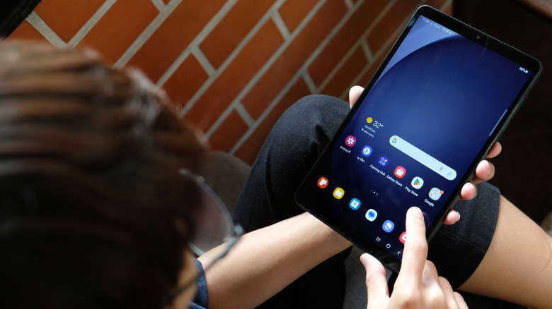 A person holding a Samsung Galaxy Tab A9+ tablet in one hand.