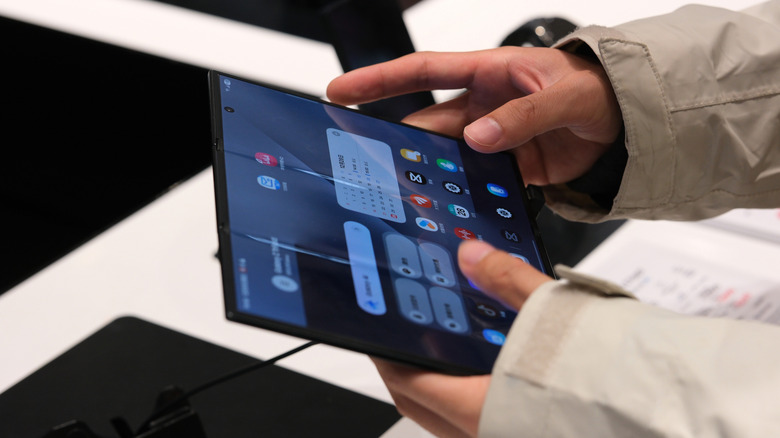 Close-up of hands interacting with a high-end Samsung Galaxy foldable device.