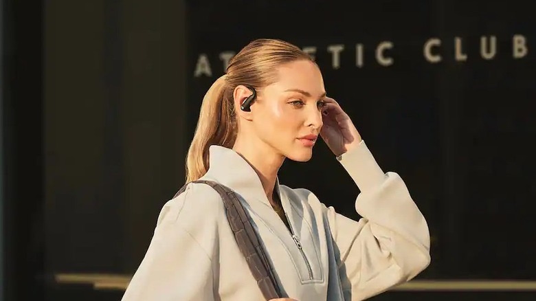 A person wearing a Beats Powerbeats Pro 2 earbud while adjusting it with their hand.