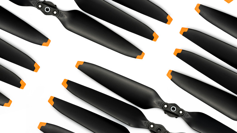 Multiple aerodynamic drone propellers arranged neatly against a plain studio background.