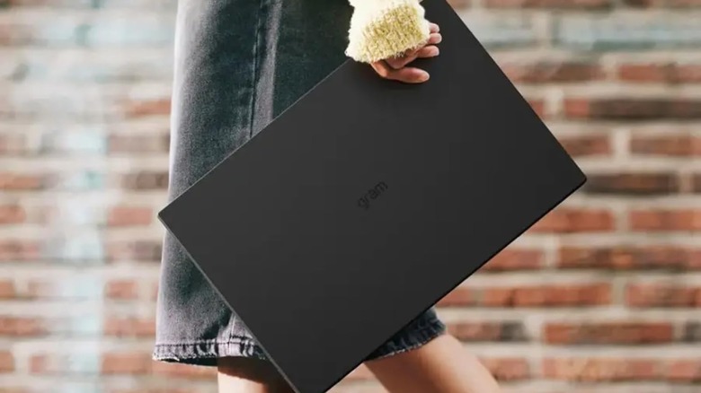 A person easily holding a 17-inch LG Gram laptop with one hand to show its lightweight build.