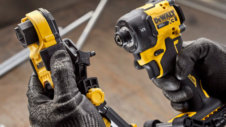 Close-up of a worker attaching a DeWalt nut runner accessory to a cordless impact driver.