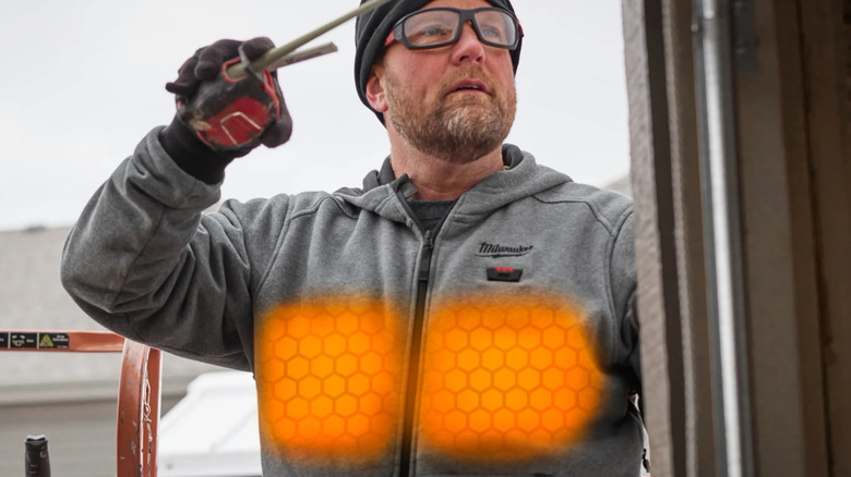A person wearing a grey Milwaukee Heated Hoodie in a cold outdoor environment.