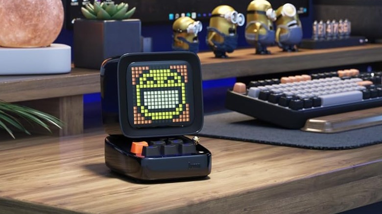 A retro-styled Divoom Ditoo speaker featuring pixel art on its screen sitting on a desk.