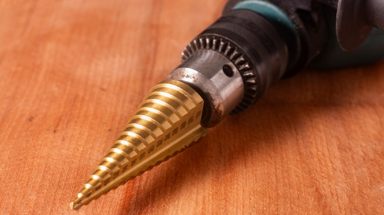 A metal step drill bit attached to a power drill.