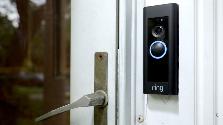A Ring Video Doorbell installed on a door frame next to a closed wooden door.
