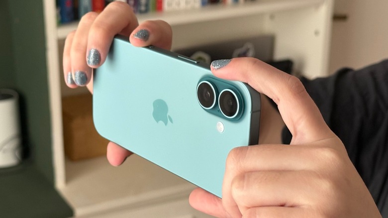 Detailed view of a hand using the Camera Control button on the side of an iPhone 16.