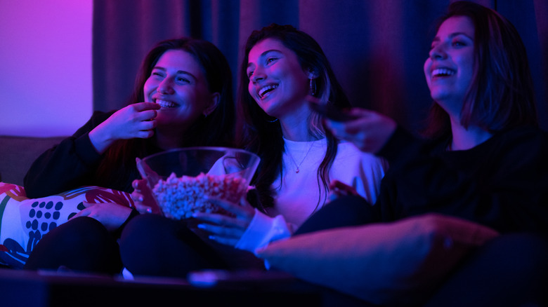 A group of friends enjoying a movie on a large screen while eating popcorn.