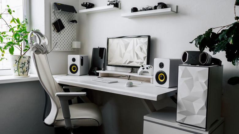 A minimalist white desk with a computer setup flanked by large repurposed speakers.