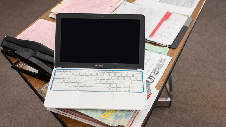 An HP Education edition Chromebook sits on a desk in a classroom setting.