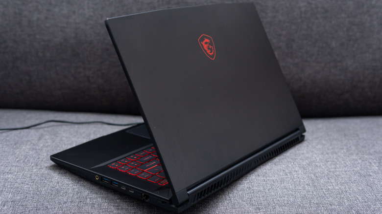 An MSI gaming laptop resting on a grey fabric sofa.