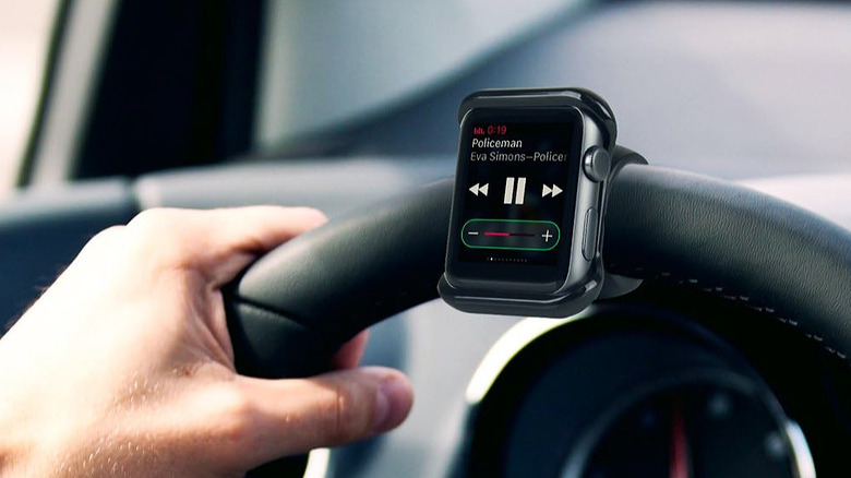 A smartwatch securely mounted to the center of a car's steering wheel.
