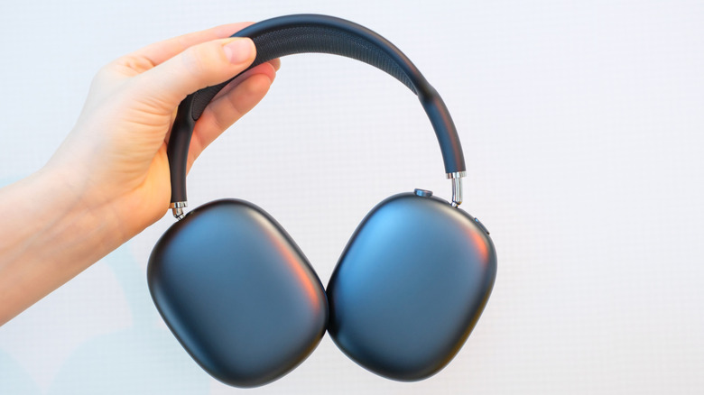 A person holding the AirPods Max by the earcup to inspect the interior drivers.