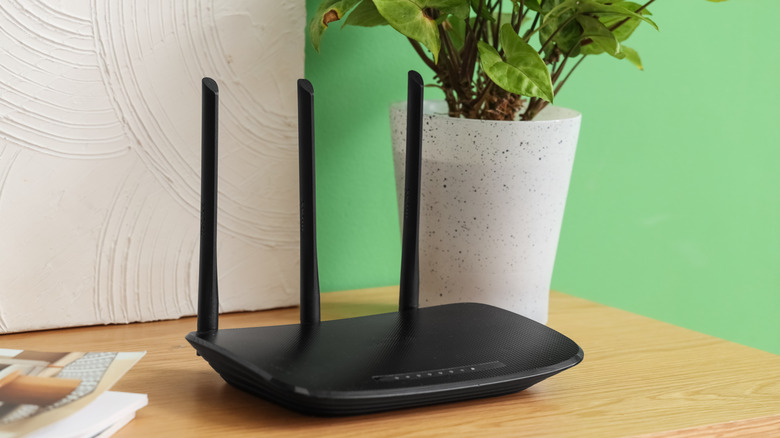 Close-up view of a black wireless router with antennas on a table.
