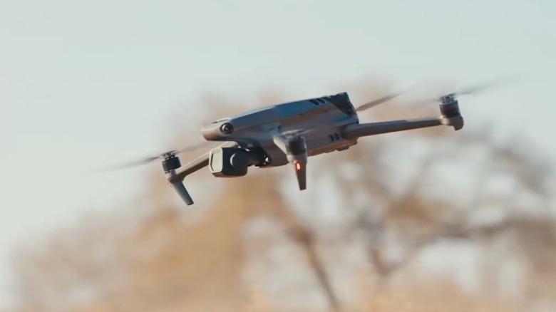 DJI Mavic 3 Classic flying outdoors with a lush green forest background.