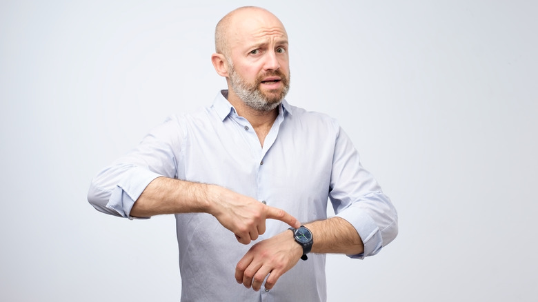 A person looking at their wristwatch with a focused or slightly anxious expression.