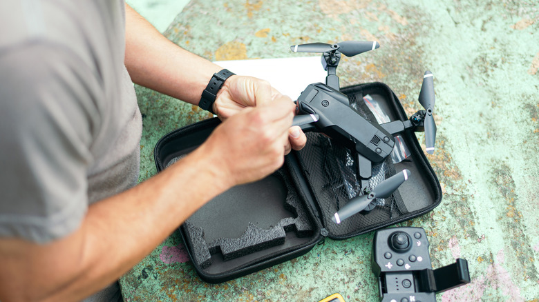 A close-up view of a technician performing maintenance on a compact foldable consumer-grade drone.