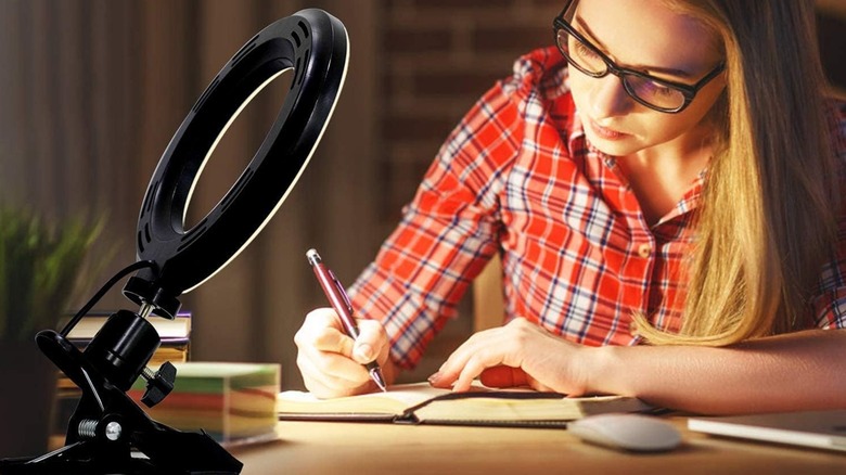 A person wearing glasses working in front of a video conference ring light setup.