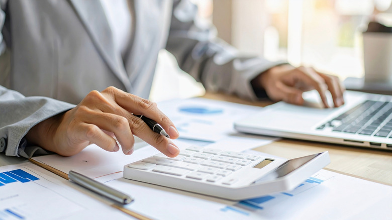 A person sitting at a table managing finances with a computer and a calculator.