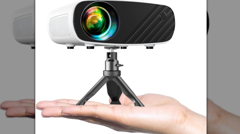 A hand holding a very small, portable mini projector to show its scale.