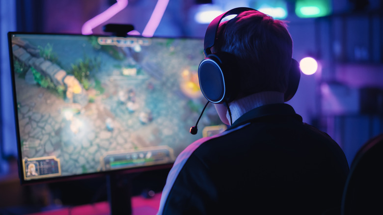 An over-the-shoulder view of a gamer playing a high-fidelity video game on a custom-built PC.