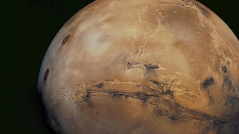 View of the reddish, dusty surface of Mars showing a thin horizon and rocky terrain.