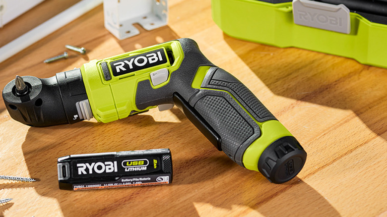 A Ryobi USB Lithium cordless screwdriver and its removable battery resting on a wooden workbench.