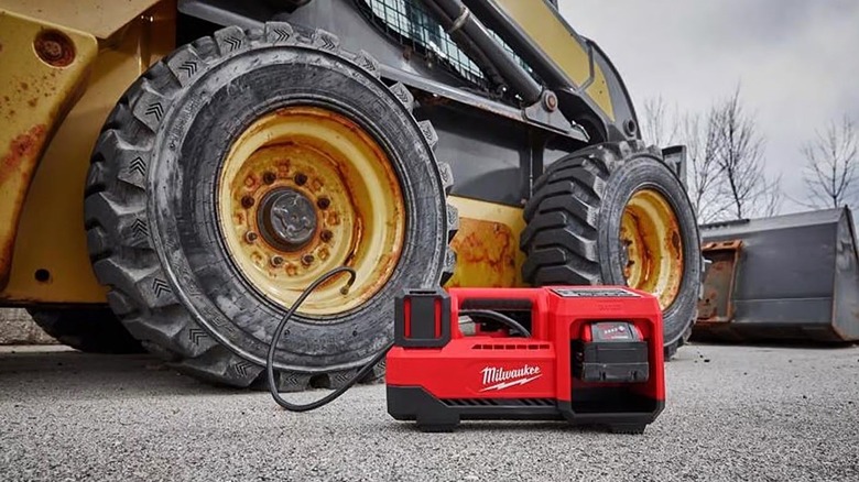 The Milwaukee M18 Cordless Tire Inflator being used to pump up a large vehicle tire.