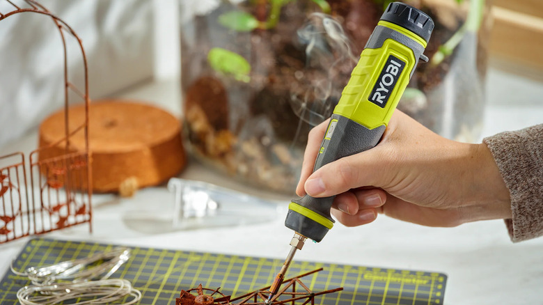 A technician using the Ryobi USB Lithium soldering pen on a green circuit board.